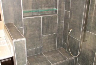 Custom tiled nich and bench with hand-held shower attachment in bathroom remodel