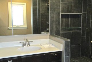Tiled kneewall between vanity and curbless shower in bathroom remodel