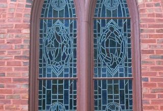 Restored historic arched window frame with stained glass