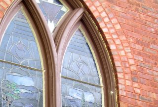 Insulated and repainted historic arched window frame with stained glass