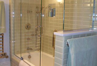Glass enclosed tiled tub with kneewall and towel holder in historic restored Victorian farmhouse in East Central IL