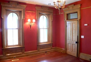 Rich red walls and restored trim in farmhouse parlor in historic restoration of Victorian Italinate Homestead in East Central IL