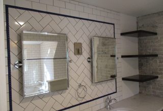 Floating shelves, cantilevered countertops, exposed brick with organic edges, period tile, and sophisticated fixtures in master bathroom remodel.