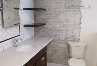 Floating shelves, cantilevered countertops, exposed brick with organic edges in master bathroom remodel.