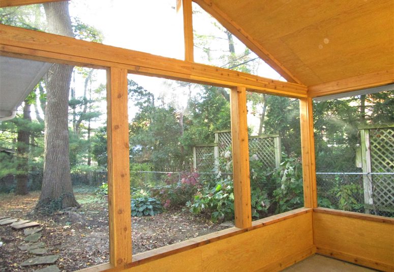 Roomy gable roof screened-in porch remodel with cedar trim and cathedral ceiling.