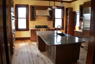Quartz countertops and butcher block, heart pine tongue-in-groove flooring in farmhouse kitchen remodel in Sydney, IL.